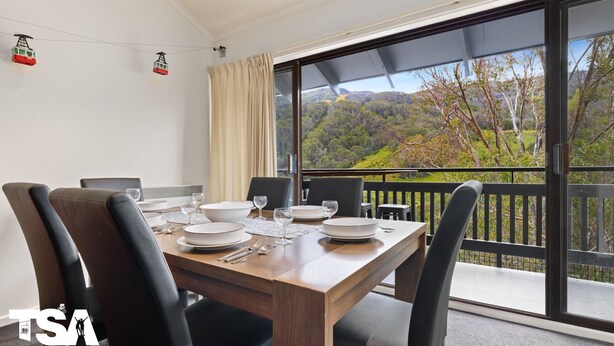 A dining area with a table set for four, large windows with a scenic view, and a cable car in the background.