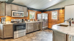 A modern kitchen with stainless steel appliances, wooden cabinetry, and a large island with a sink. - Lake Escape w/ Hot Tub & Docks in Hope! (Hope)