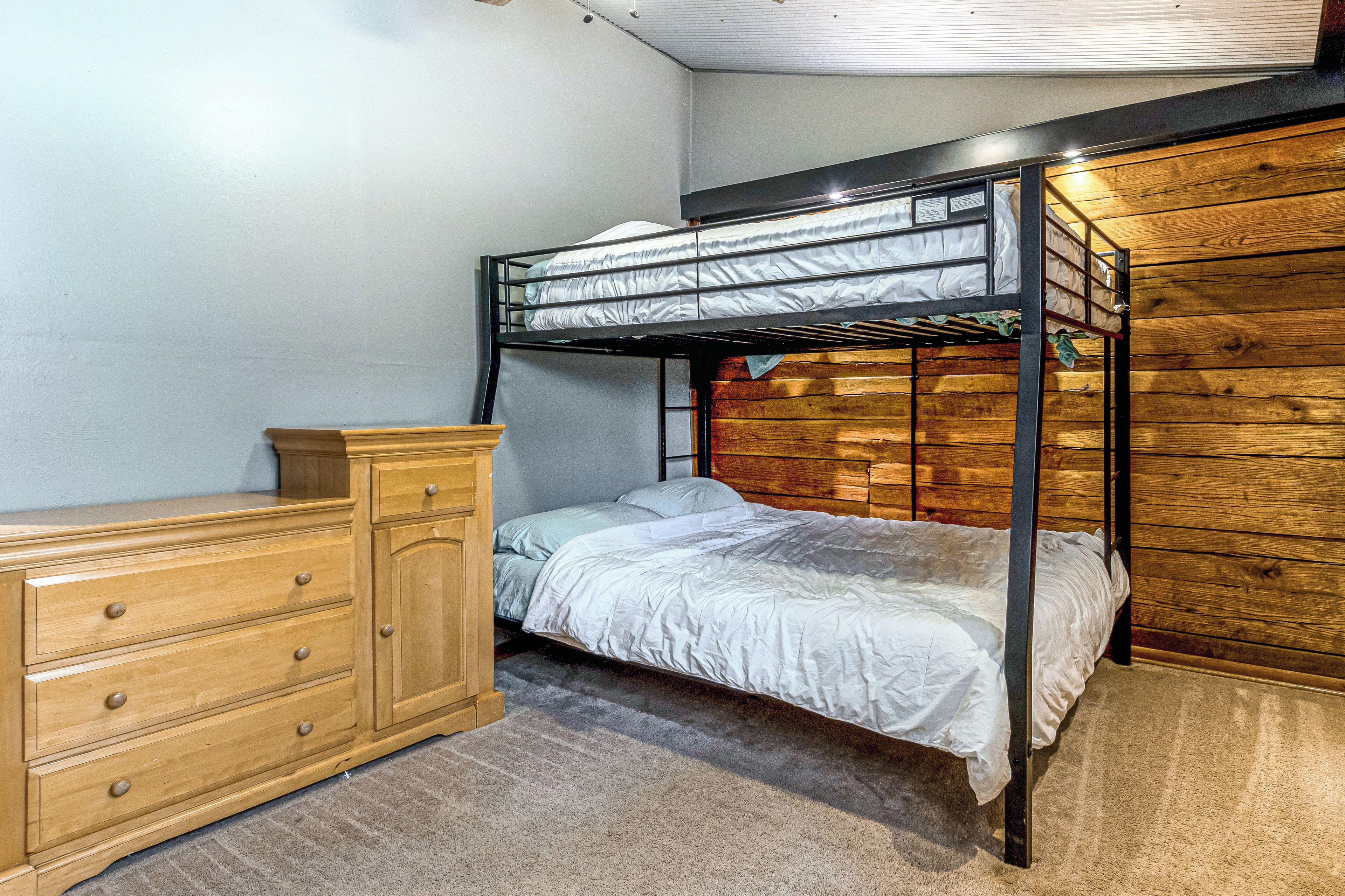 Une chambre avec un lit superposé doté d’une tête de lit en bois, une commode en bois avec des tiroirs et un sol recouvert de moquette.