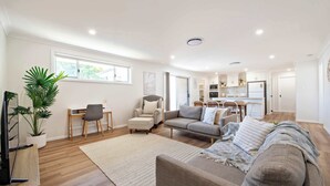 Een moderne woonkamer met een bank, fauteuil en een eethoek.