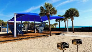 A beach playground with a blue canopy, palm trees, and barbecue grills. - Renovated Rotonda West Oasis w/ Private Pool (Rotonda West)