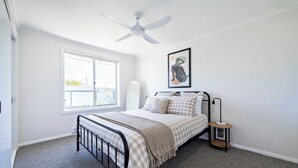 A bedroom with a bed, a ceiling fan, a window, and a framed artwork on the wall. - Cozy Getaway - Modern Central Unit | Garden View (Dubbo)