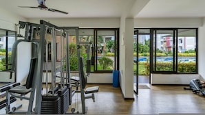 A gym with exercise equipment, large windows, and a ceiling fan. - 1BR w Pool Sauna Near Calangute Baga Beach (Calangute)