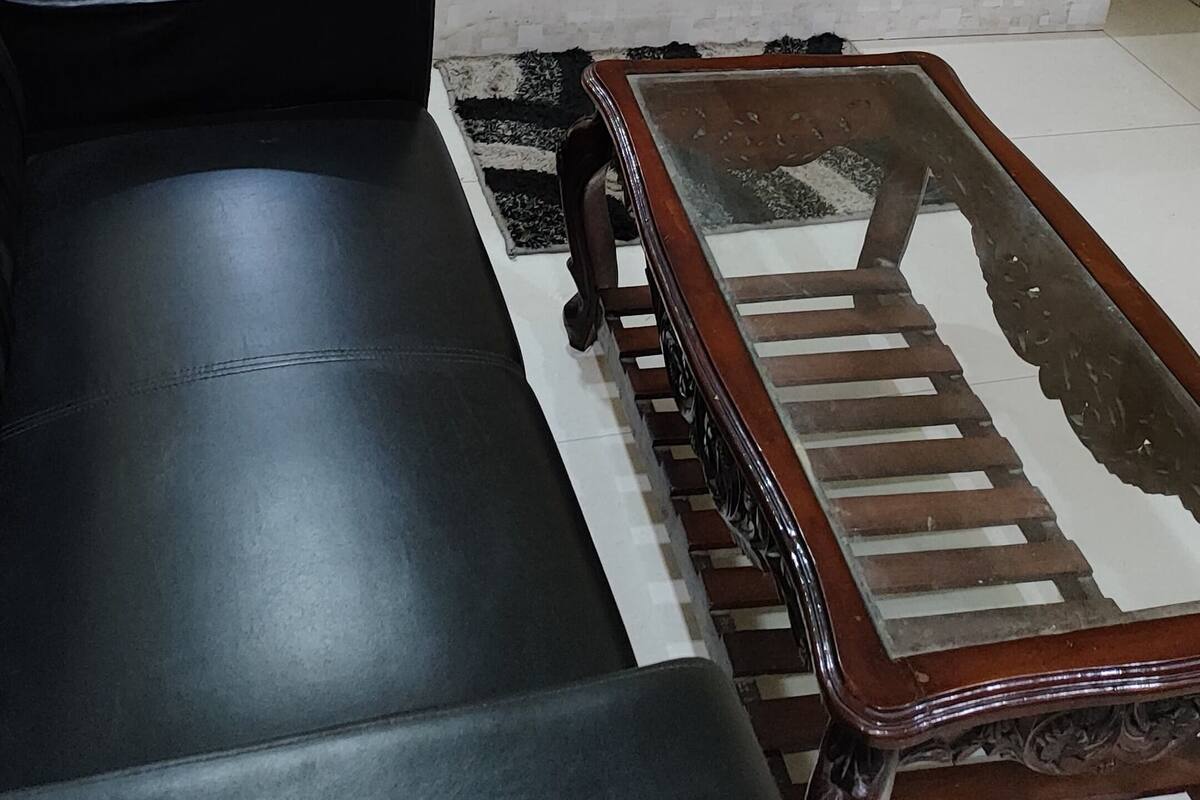 Un dormitorio con una cama, mesitas de noche, un sofá negro y una mesa de centro de madera.