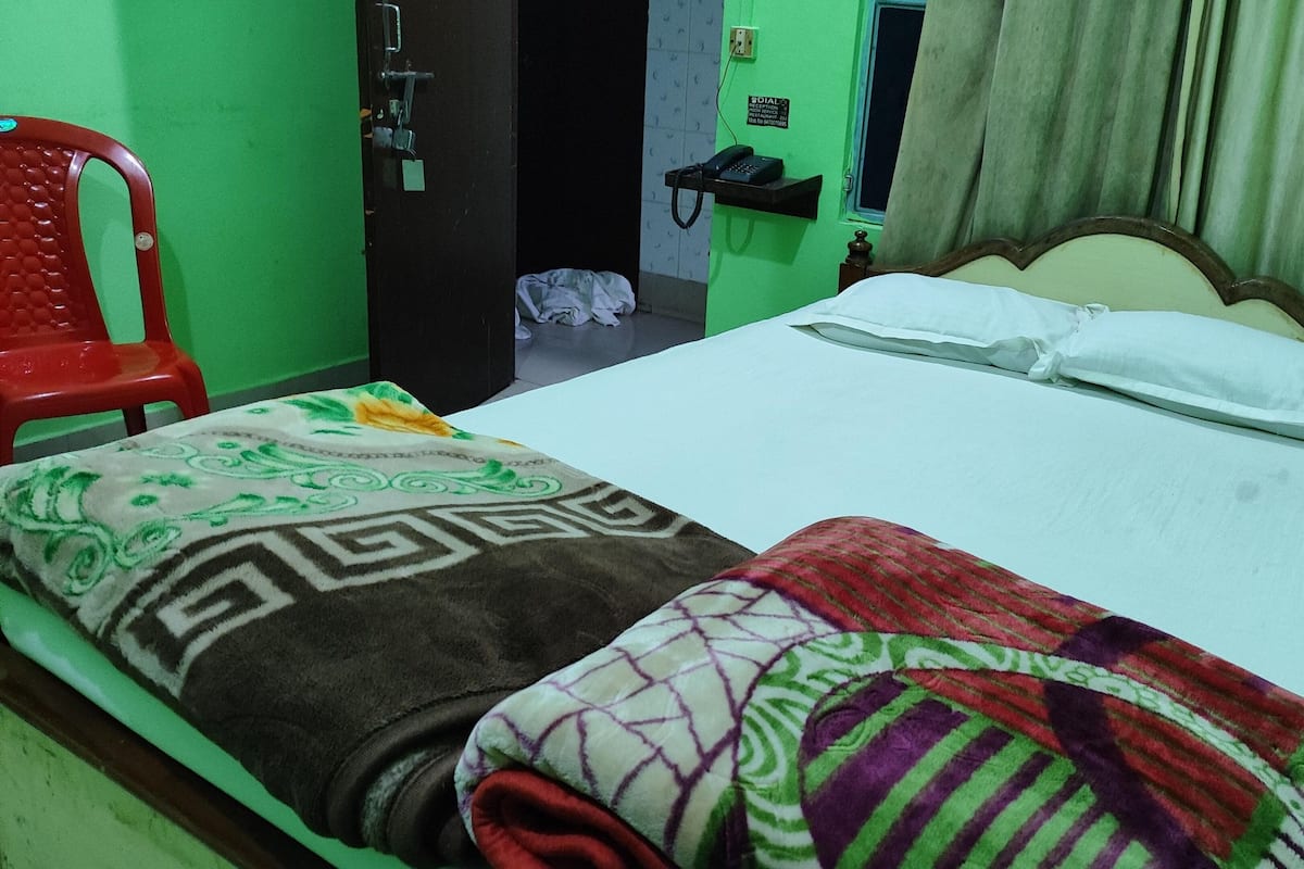 Una habitación con una cama, una silla roja, un teléfono y una puerta.