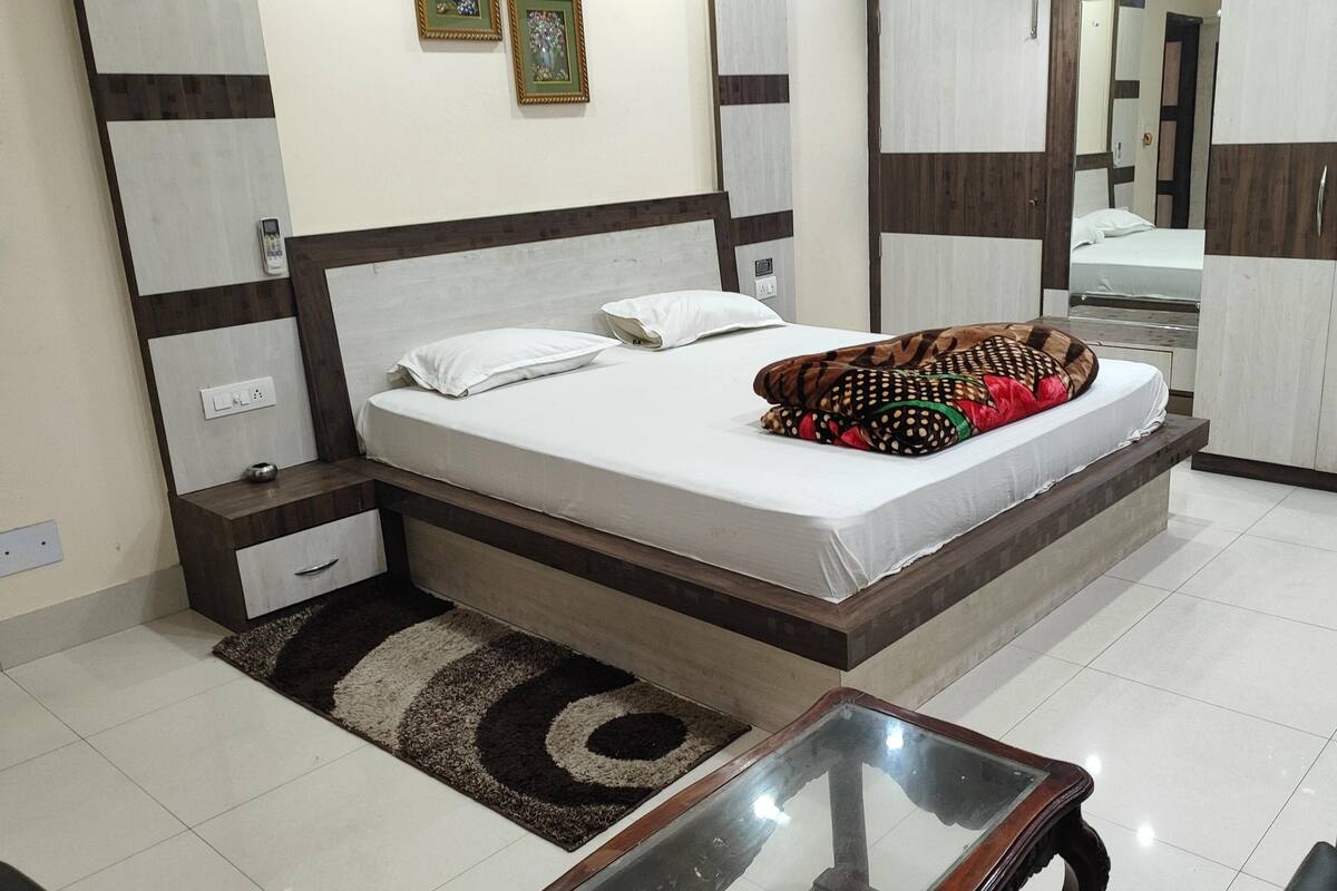 Un dormitorio con cama, mesitas de noche, un espejo y una pequeña mesa.
