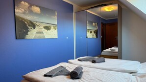 Een hotelkamer met twee bedden, een grote spiegel en een schilderij van een strand.