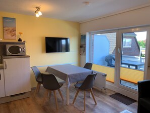Enjoy a homey atmosphere in this cozy room featuring a kitchenette, flat-screen TV, and dining area with a sliding glass door leading to an outdoor space.