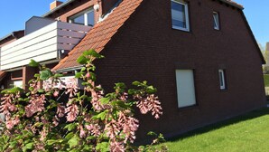 Een herenhuis met twee verdiepingen, bakstenen gevel, schuin dak en een klein voortuintje.