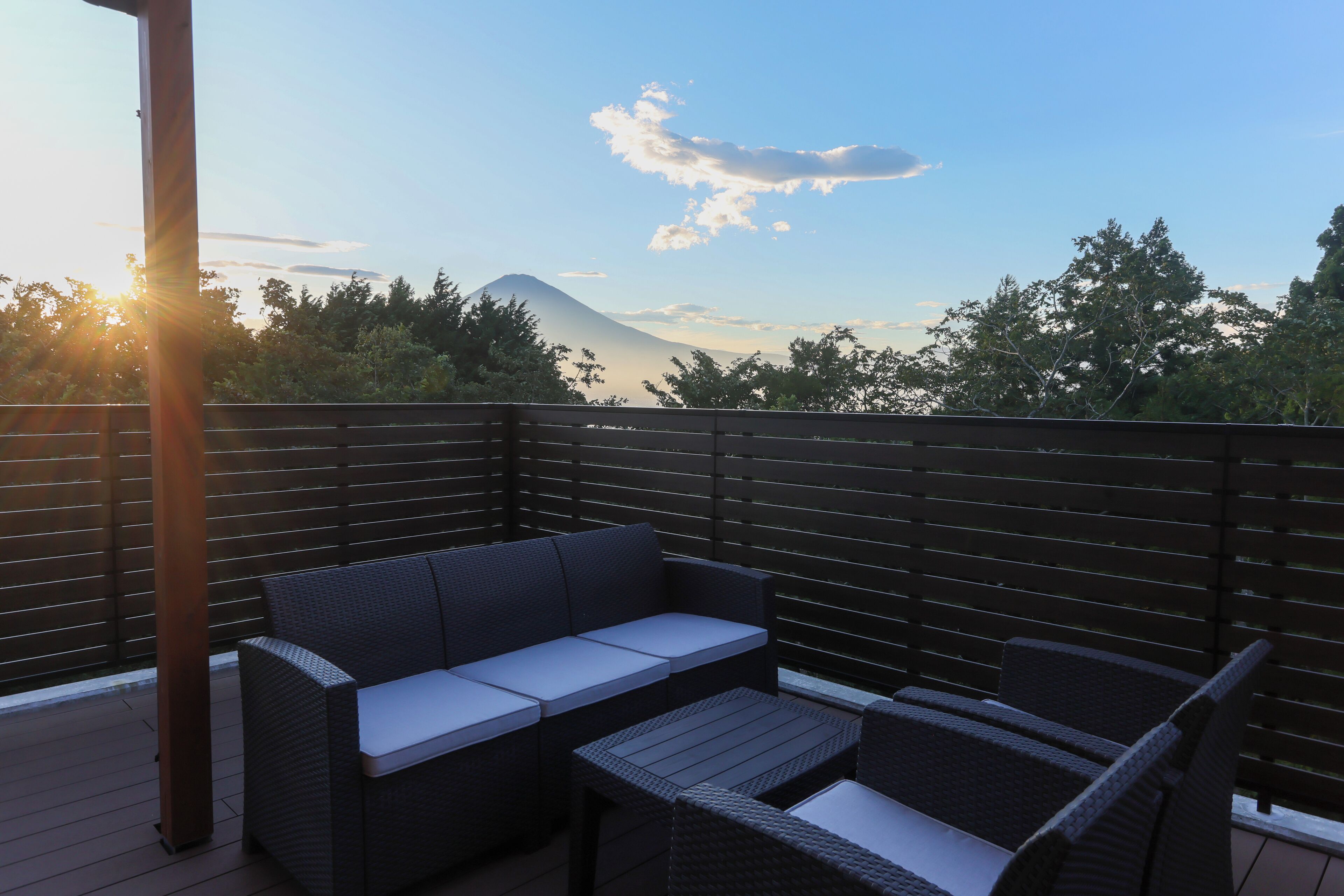 Terraza con mobiliario de mimbre y vistas a una montaña.