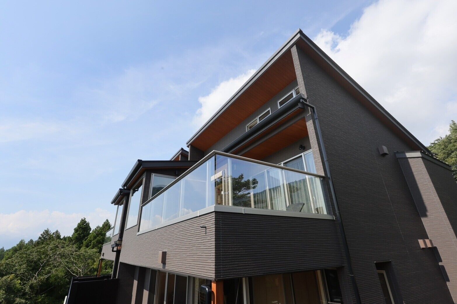 Een modern gebouw met twee verdiepingen, grote glazen balkons en een plat dak.