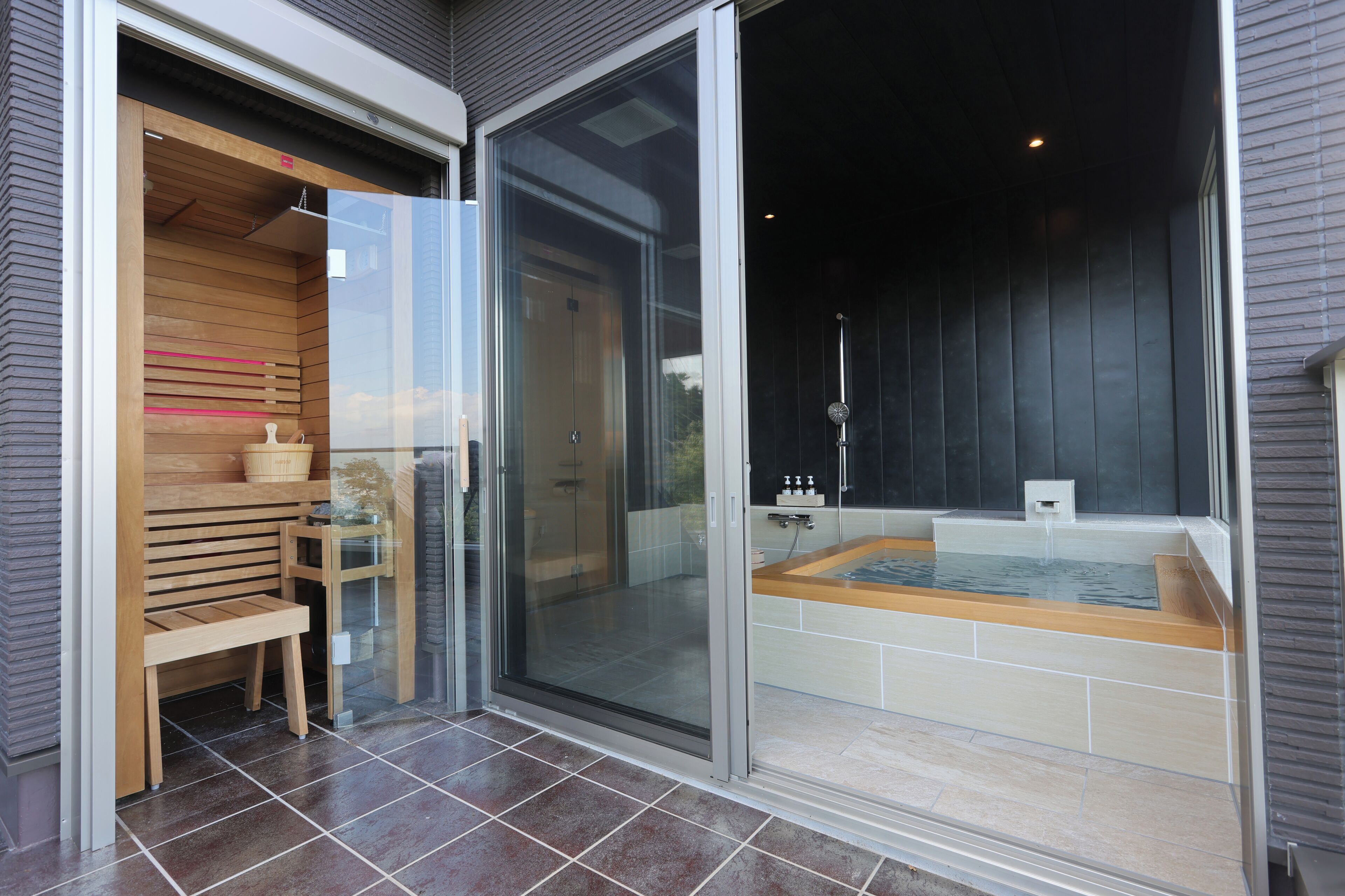 A modern bathroom with a glass shower enclosure, a wooden bench, and a bathtub.