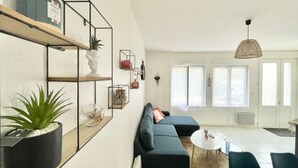 A modern living room with a sectional sofa, a dining area with a round table, and a kitchen in the background. - Le Benodet Centre. In the center of town 200m from the beach (Bénodet)
