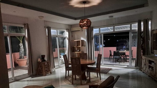 Een moderne eetruimte met een ronde tafel, stoelen en een hanglamp.