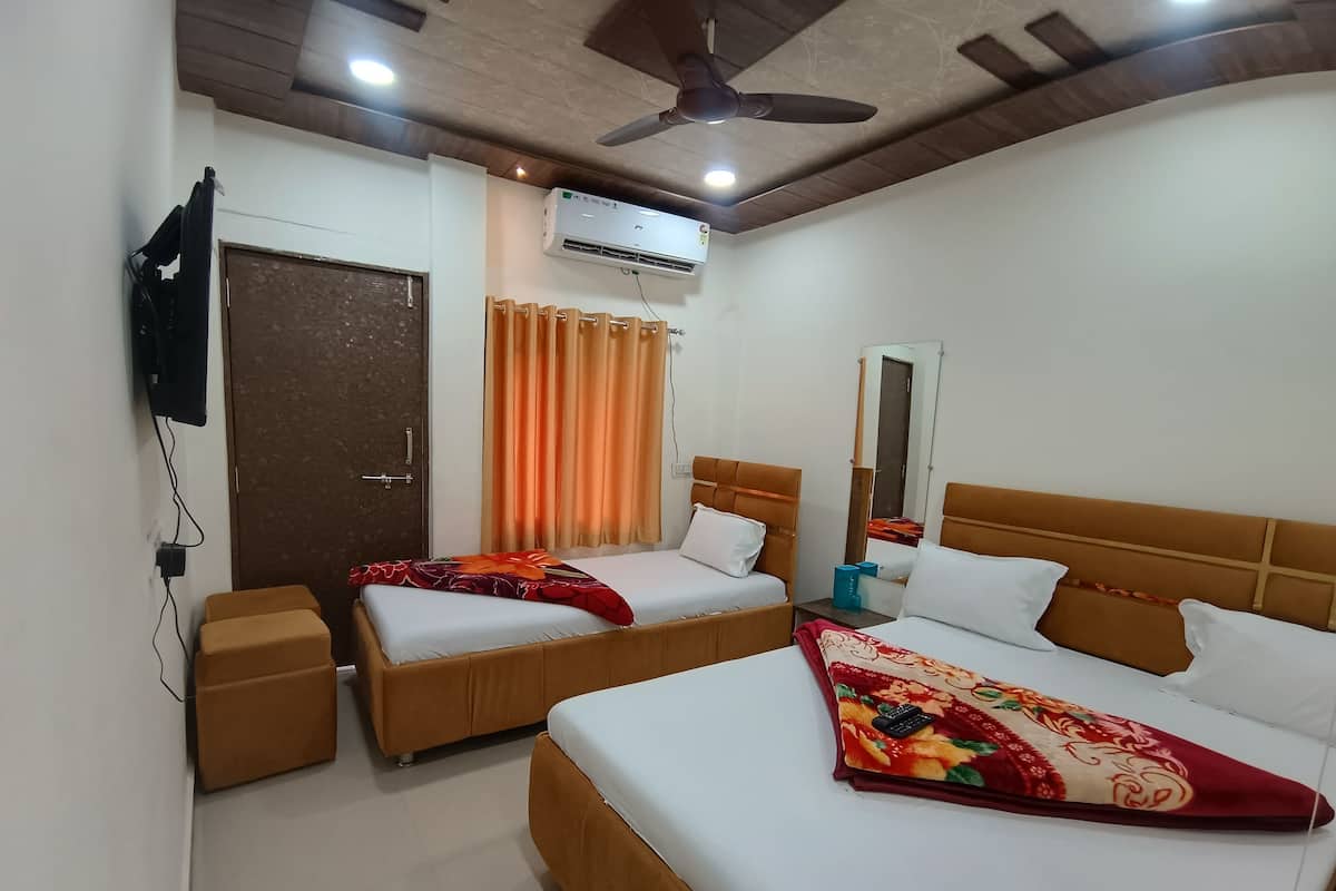 A hotel room with two beds, a ceiling fan, an air conditioning unit, a TV mounted on the wall, and a door with a handle.