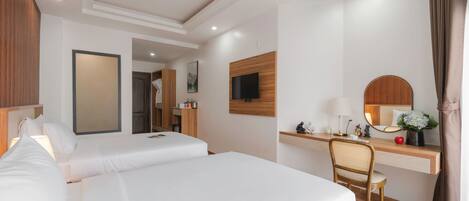Quarto de hotel com duas camas, uma escrivaninha, uma cadeira, uma televisão e um espelho.