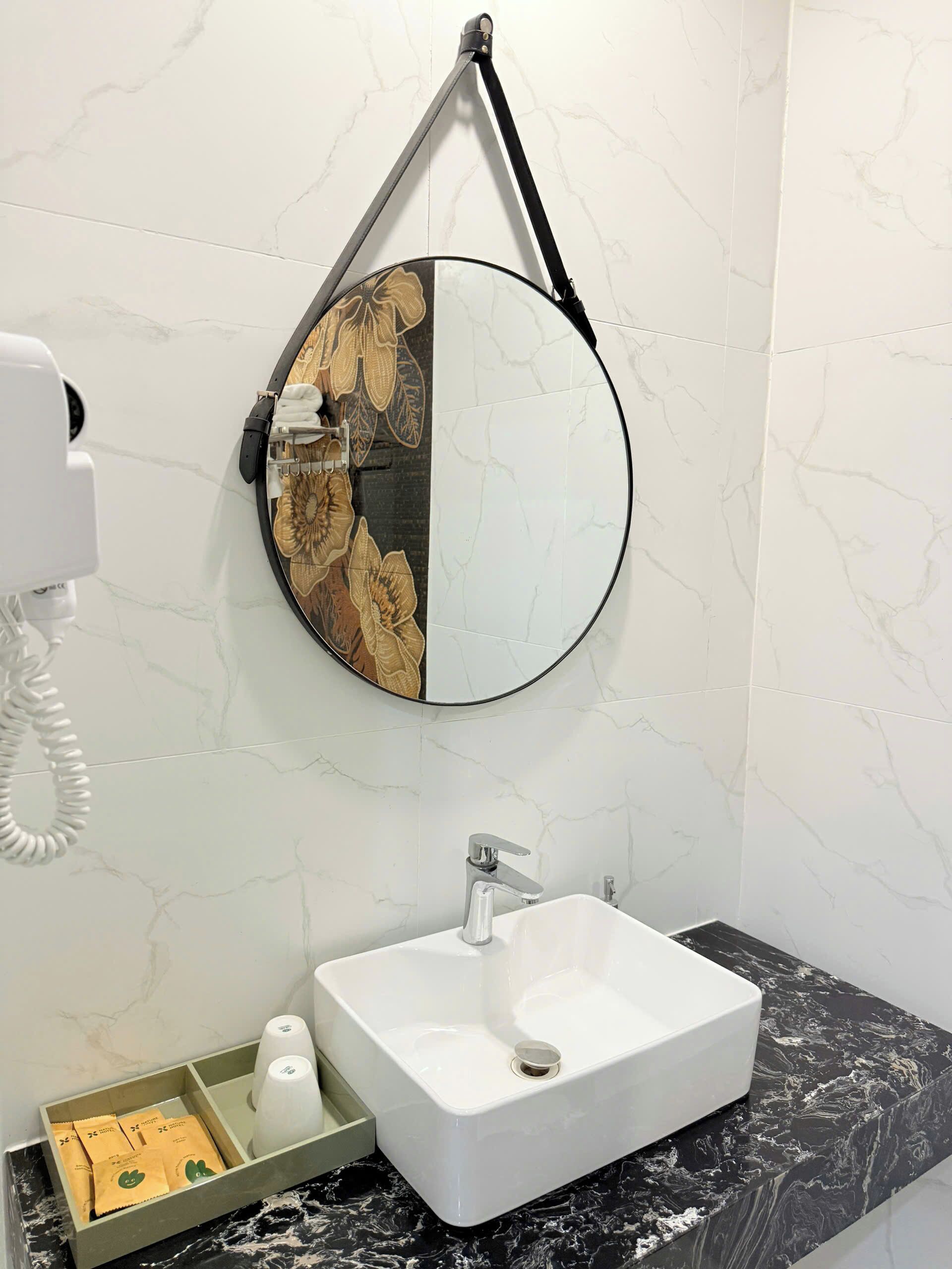A bathroom with a white sink, a mirror with a decorative frame, and a towel rack.