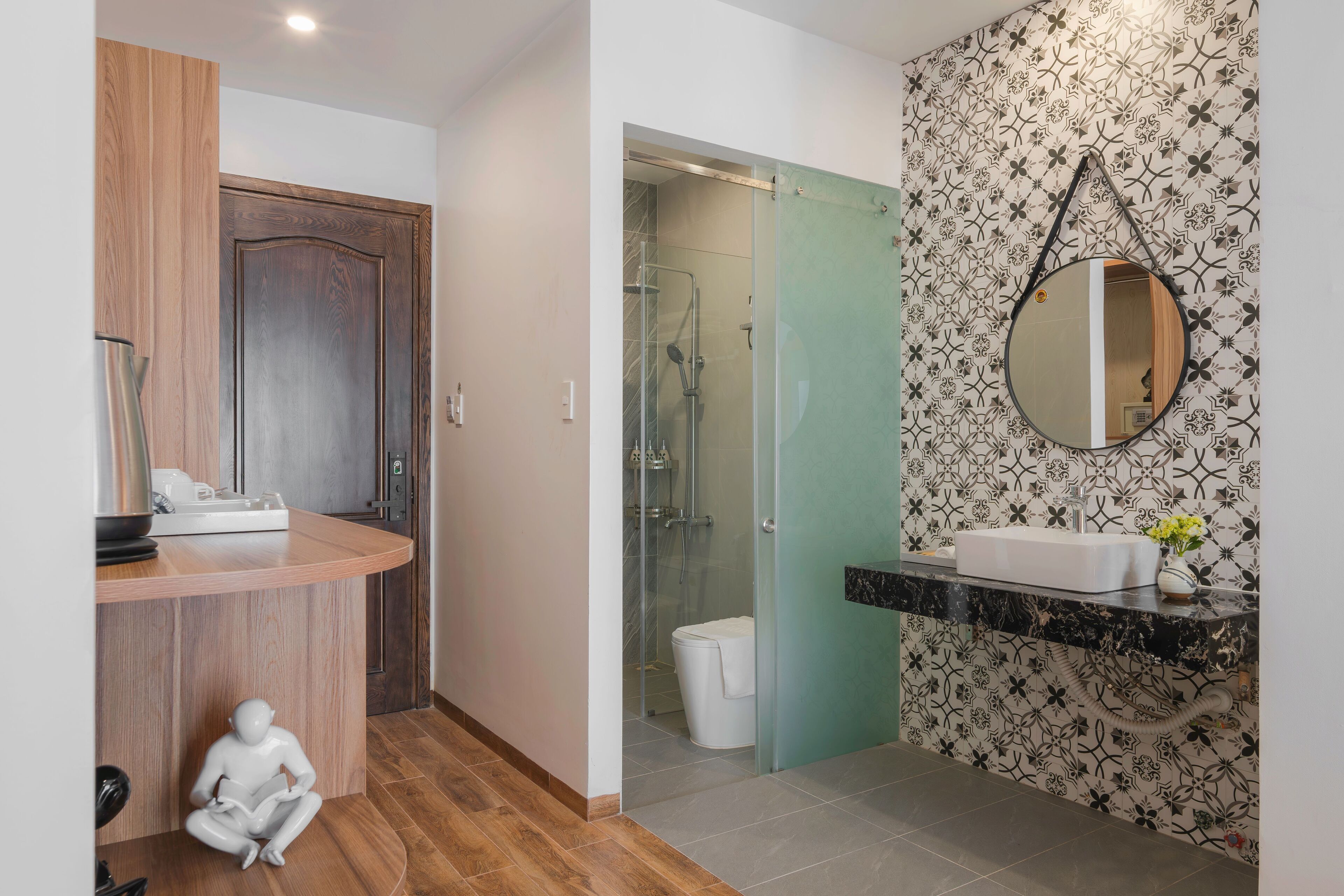 A modern bathroom with a wooden vanity, a glass shower enclosure, and a decorative mirror.
