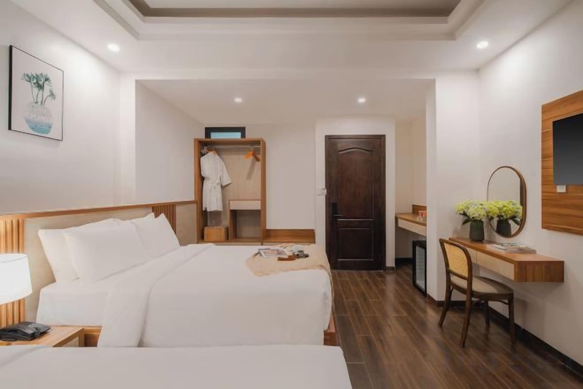 Une chambre d’hôtel comprenant un lit, un bureau, une chaise, une armoire et un miroir.