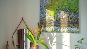 Un miroir, un vase avec des fleurs et un tableau accroché au mur.