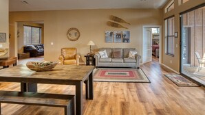 A spacious living room with a wooden floor, a dining table, a sofa, and a coffee table.