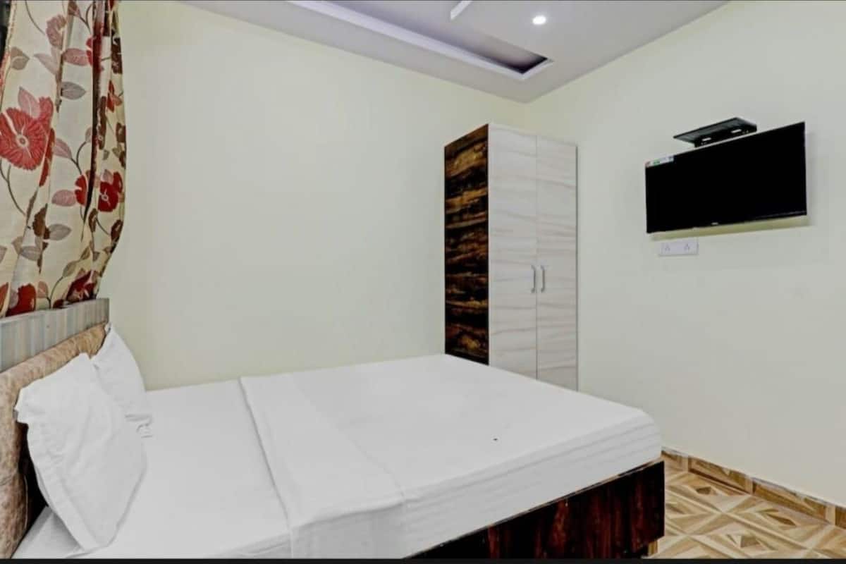 A bedroom with a bed, a wardrobe, and a mounted TV.