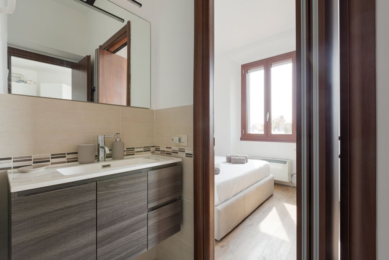 A modern bathroom with a large mirror, a sink, and a toilet.
