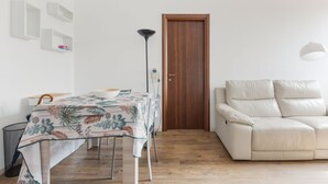 Um quarto com uma mesa de jantar, um sofá, uma porta de madeira e um abajur.