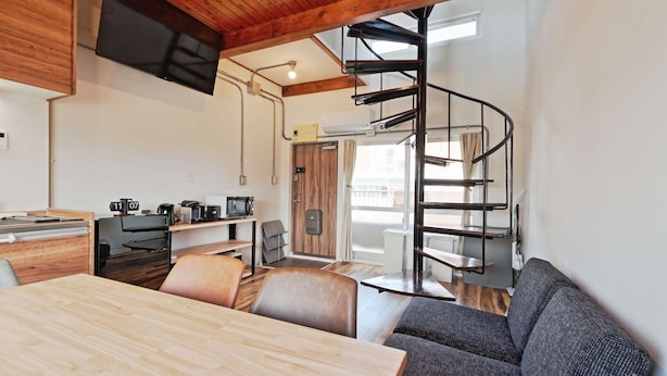 A modern kitchen with a wooden ceiling, a dining area with a wooden table and chairs, and a spiral staircase leading to an upper level. - There are 1 bed room with 2 double beds (渋谷区)
