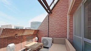 A rooftop terrace with a glass table, wicker furniture, and an air conditioning unit. - There are 1 bed room with 2 double beds (渋谷区)