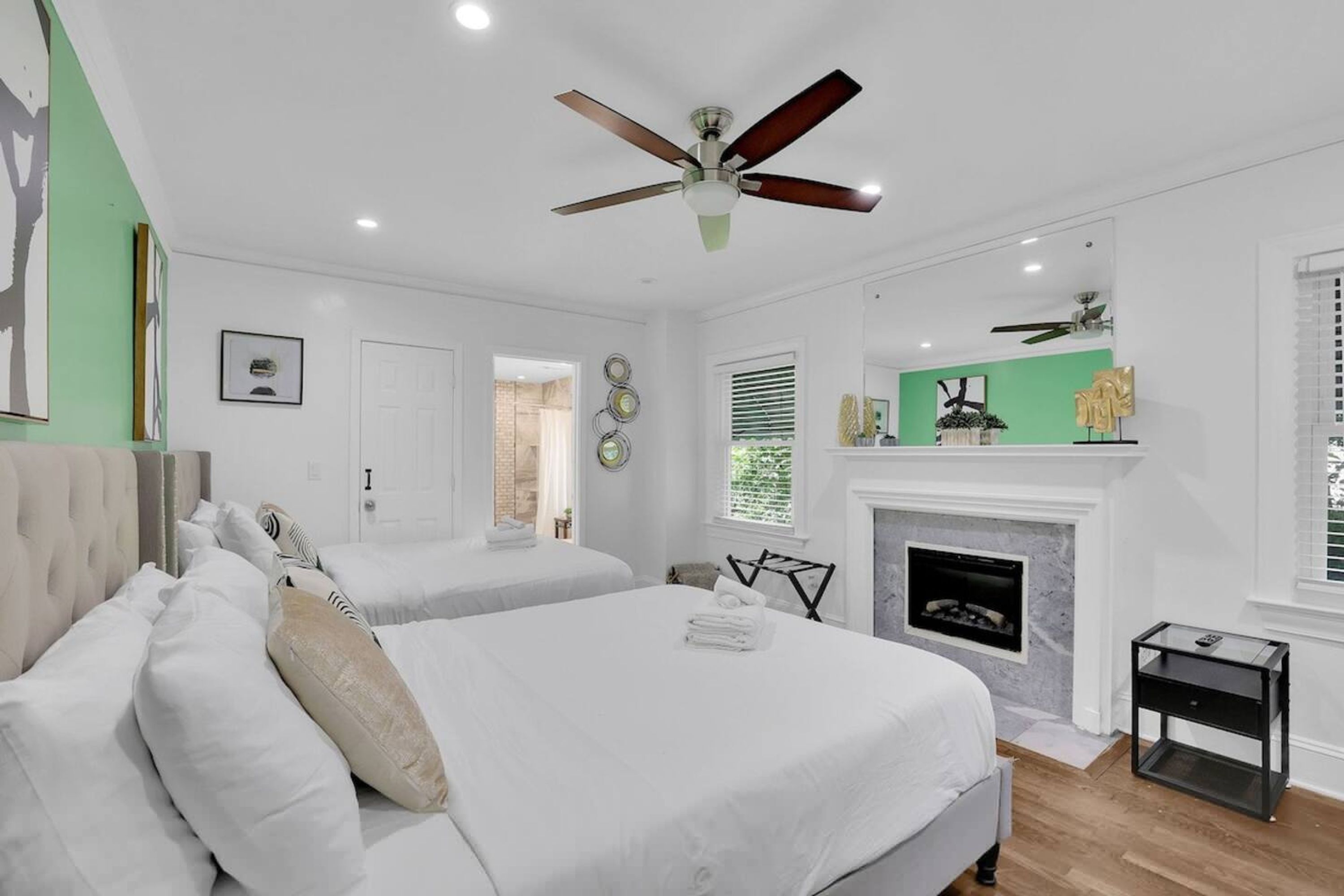 A bedroom with two beds, a fireplace, and a ceiling fan.