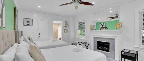 A bedroom with two beds, a fireplace, and a ceiling fan.