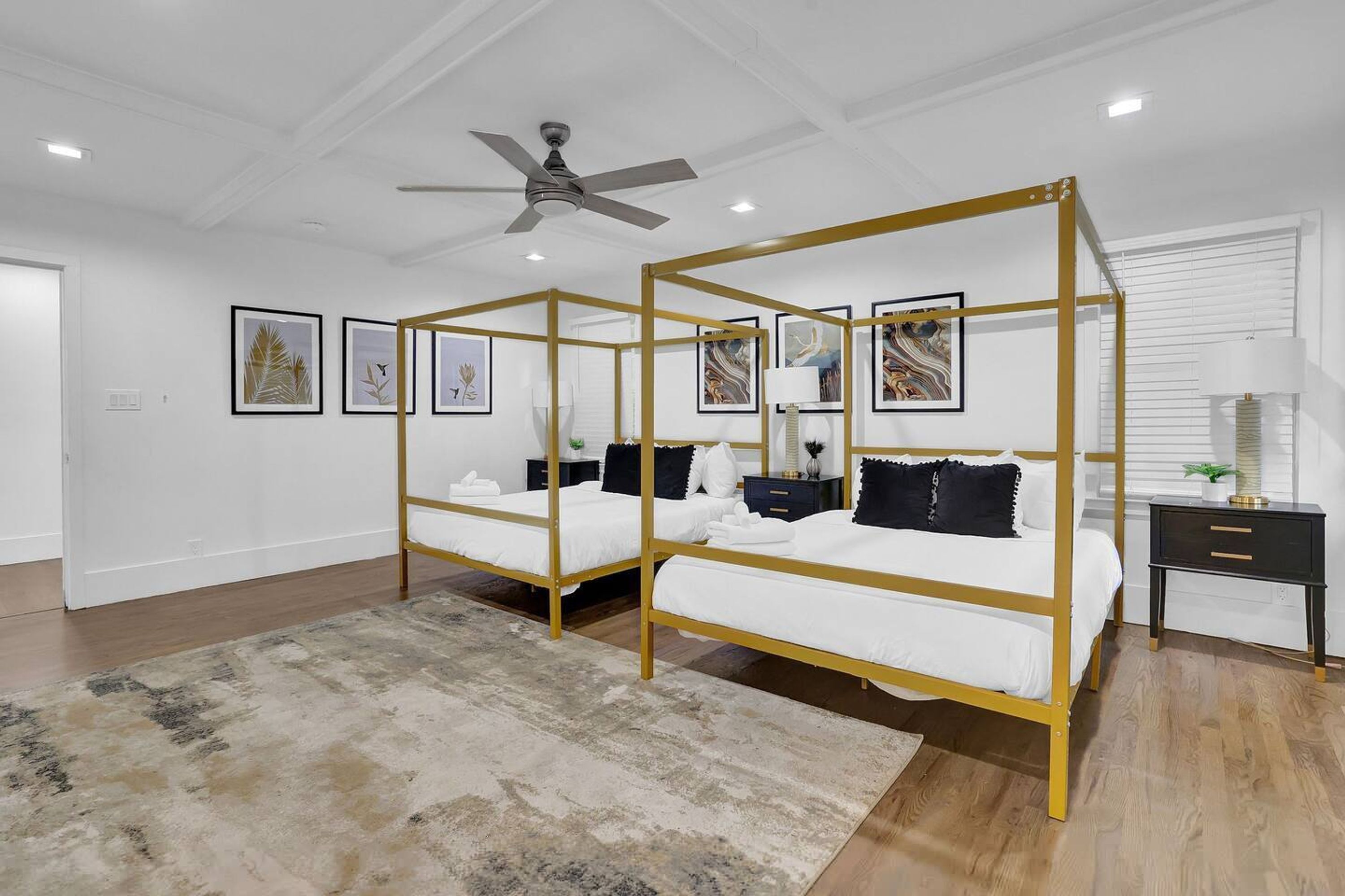 A bedroom with a four-poster bed, a ceiling fan, and framed artwork on the walls.
