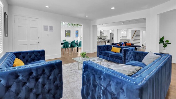 Un salon moderne avec un canapé bleu, une table basse en verre et un coin repas avec des chaises vertes.