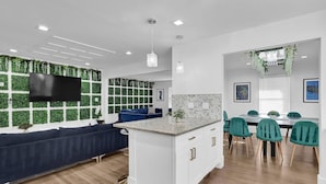 Une cuisine moderne dotée d’un îlot central, de meubles blancs et d’un coin repas avec des chaises vertes.