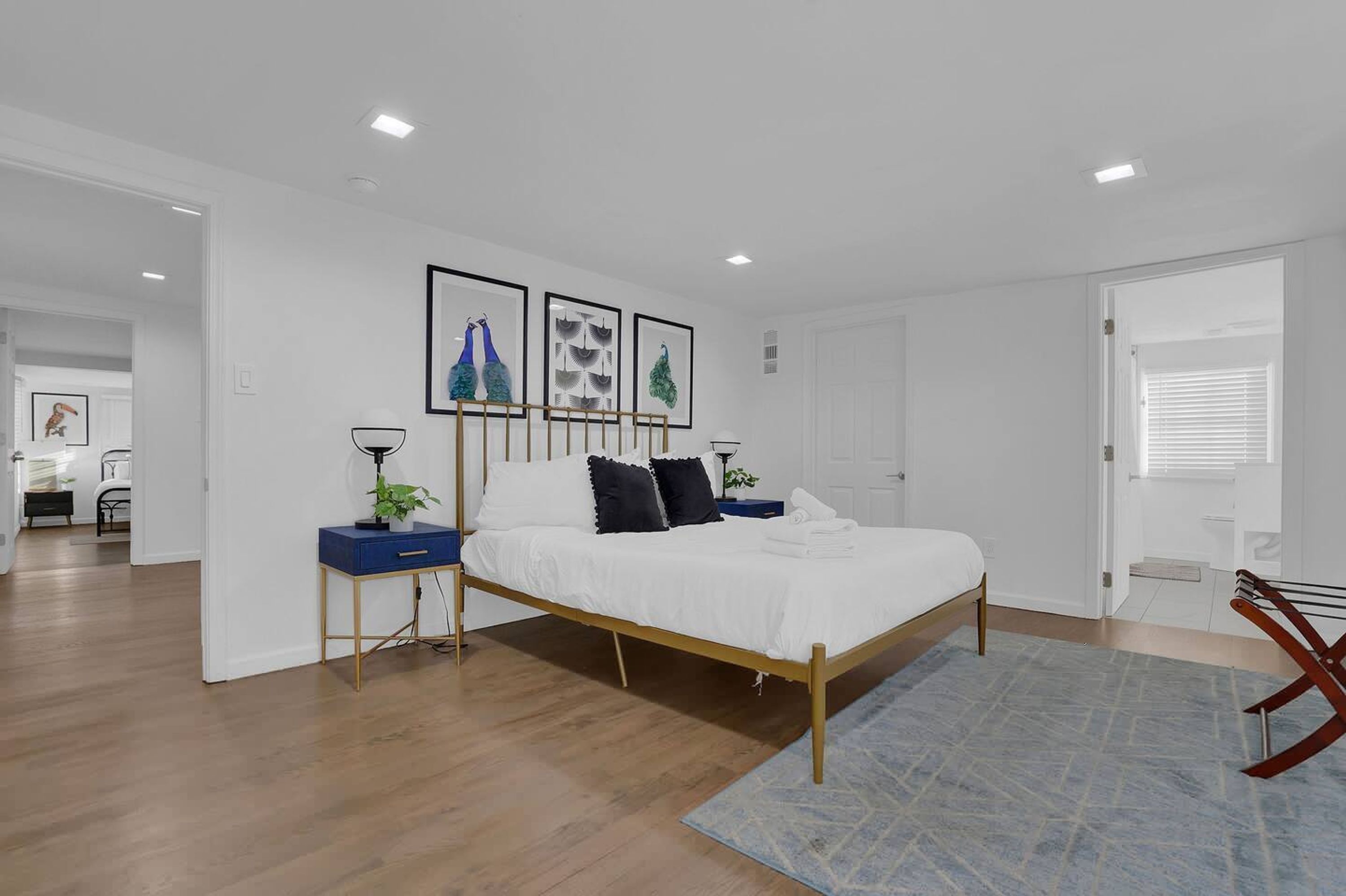 A modern bedroom with a wooden bed, white bedding, and a blue accent wall.