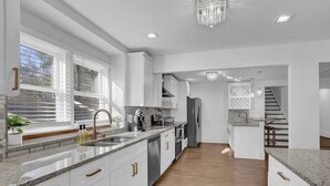 Une cuisine moderne avec des meubles blancs, des plans de travail en granit et des appareils électroménagers en acier inoxydable.