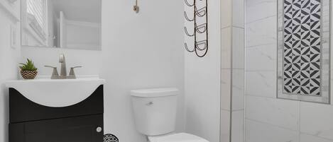 A bathroom with a toilet, sink, and shower.