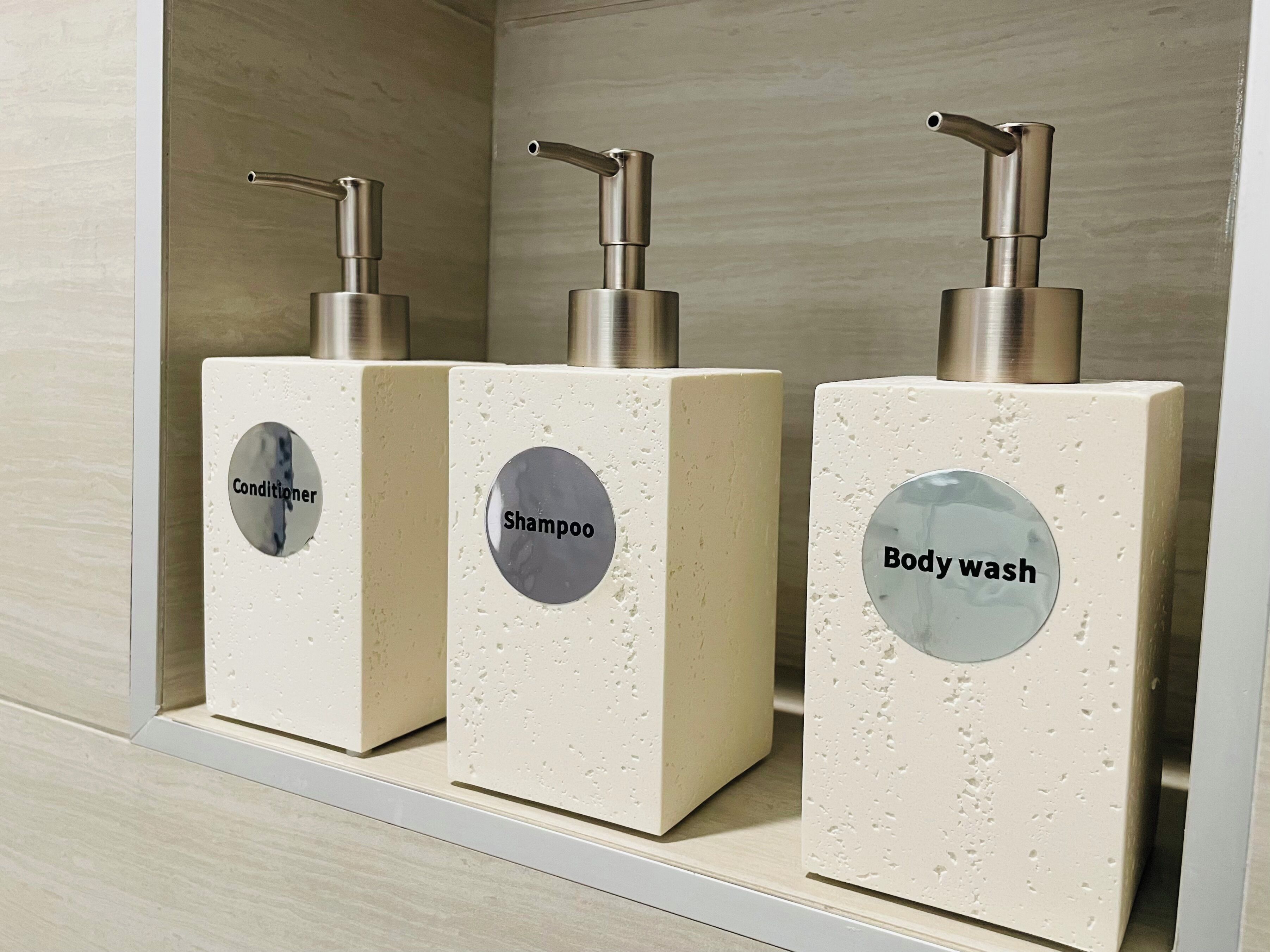Tre erogatori per prodotti da bagno con le scritte 