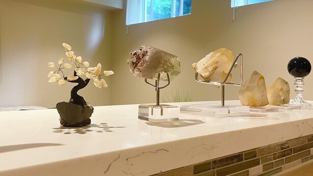 Una cocina moderna con encimera de mármol, un bonsái y esculturas decorativas de cristal.