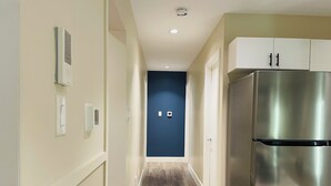 Una cocina moderna con un refrigerador de acero inoxidable, piso de madera y una pared de acento azul.