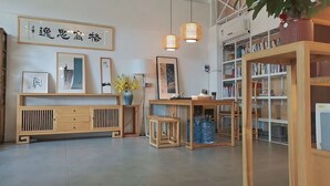 A room with a wooden console table, framed artwork, a bookshelf, and hanging pendant lights. - JINJU ART HOTEL (Guangzhou)