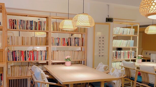 A cozy bookstore with wooden shelves and tables, featuring a variety of books and decorative elements like potted flowers. - JINJU ART HOTEL (Guangzhou)