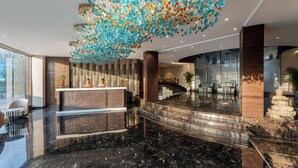 A modern lobby with a marble floor, a reception desk, and a decorative ceiling. - Ginger Hyderabad Airport Road (Hyderabad)