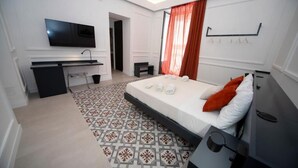 Una habitación de hotel moderna con cama, escritorio, televisor y una alfombra estampada.