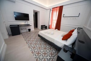 Una moderna camera d'hotel con un letto, una scrivania, una televisione e un tappeto decorato.