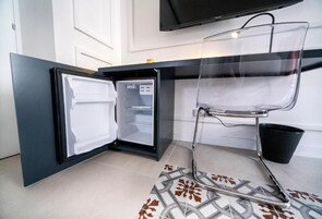 Una cucina compatta con frigorifero integrato, una sedia trasparente e un pavimento piastrellato.