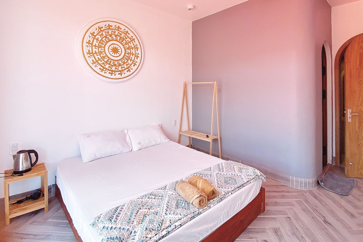 A bedroom with a bed, a wooden shelf, a wall decoration, and a wooden door.