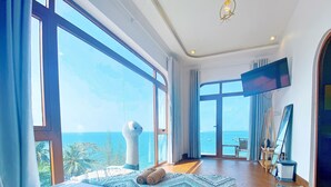 A spacious room with large windows, a view of the sea, and a modern interior design. - Coco Bay Hòn Sơn (Kien Hai)