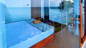 A modern room with a glass wall, a bed, a small table, and a view of the sea. - Coco Bay Hòn Sơn (Kien Hai)